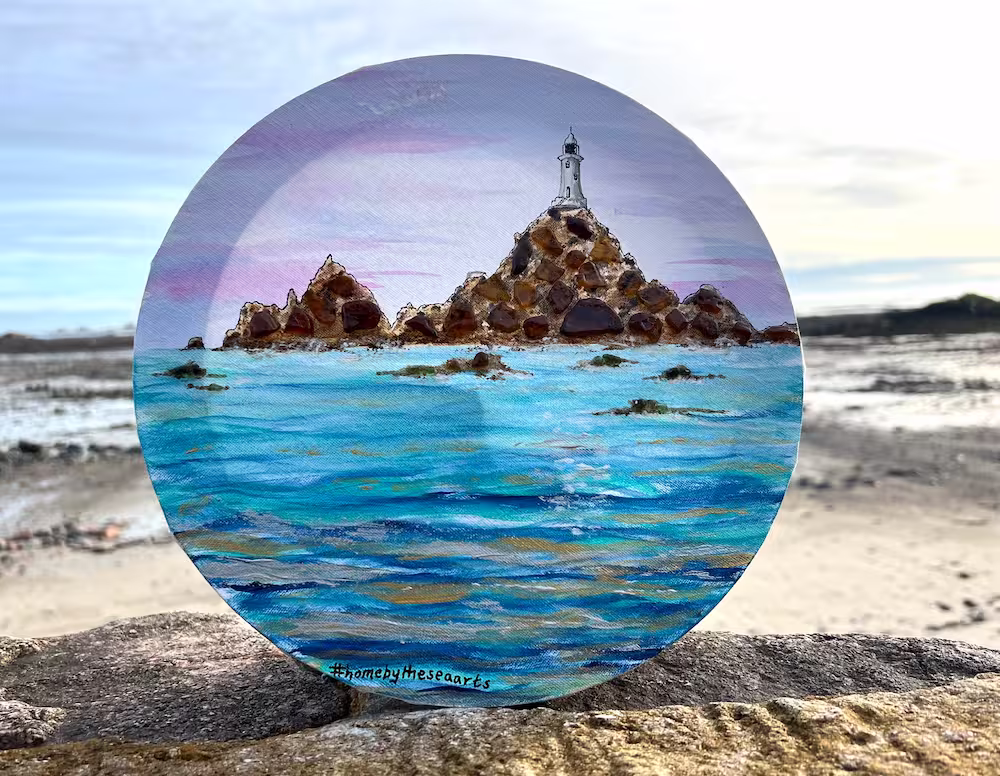 Circular canvas artwork of Corbiere Lighthouse with golden sea reflections and brown sea glass detailing on the rocky shoreline, 30cm in diameter.