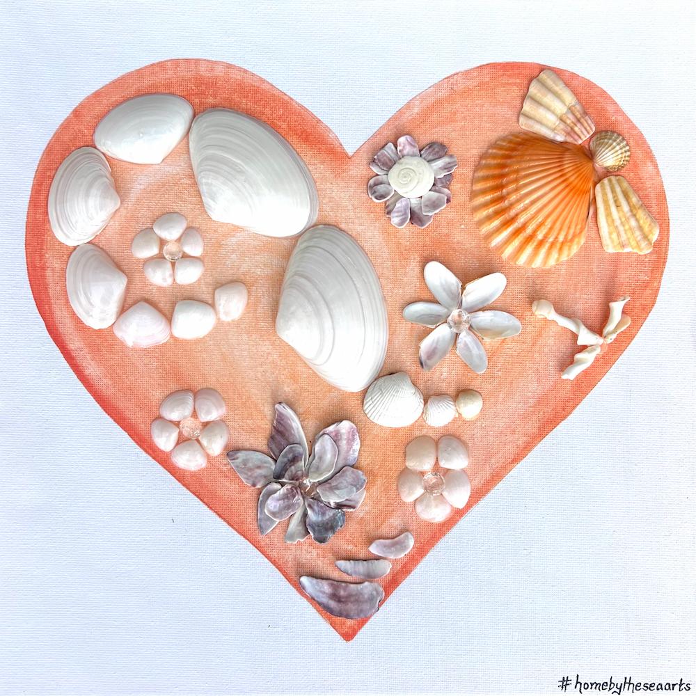Heart-shaped artwork made with assorted foraged seashells from Florida and South Africa, arranged on a peach-colored background canvas.